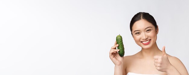 Asian young woman over isolated background holding cucumber