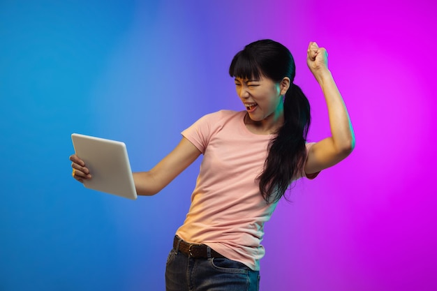 Asian young woman's portrait on gradient in neon