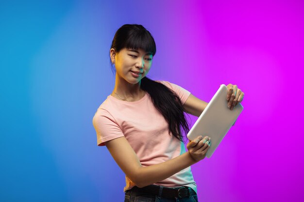 Asian young woman's portrait on gradient studio in neon