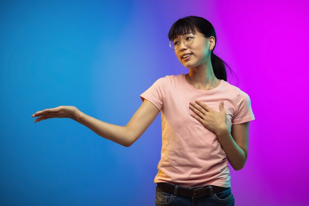 Asian young woman's portrait on gradient studio wall