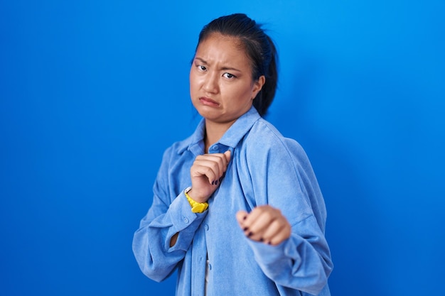 Free photo asian young woman standing over blue background disgusted expression displeased and fearful doing disgust face because aversion reaction