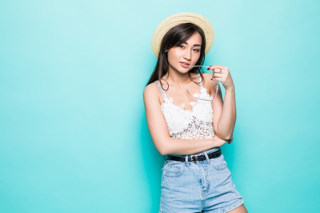 Asian young woman in summer clithes and straw hat isolated on green wall