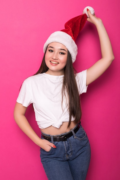 Asian young woman wearing Santa's hat isolated on pink wall