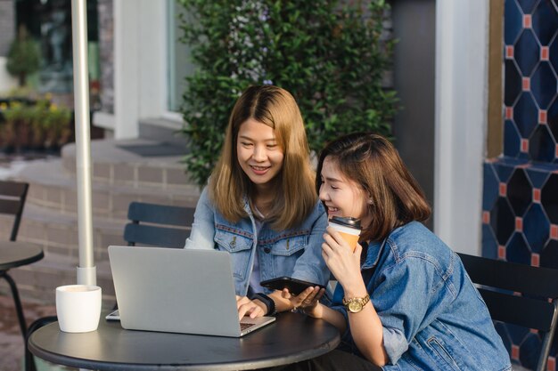 Asian young women in smart casual clothes working sending email on laptop and drinking coffee while 