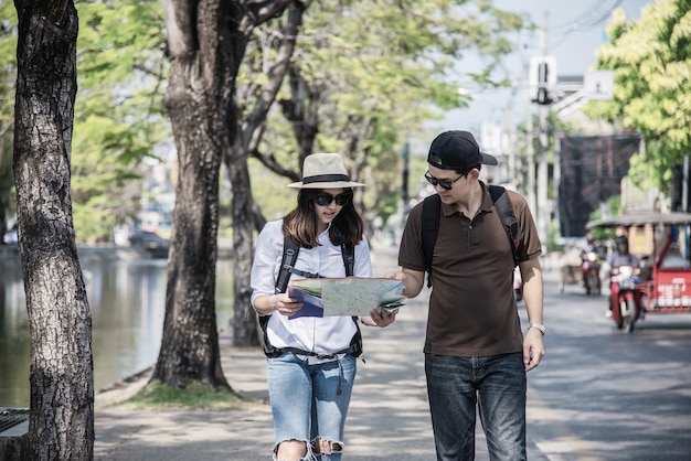 Asiancouple観光客が道路を横断する市内地図を保持