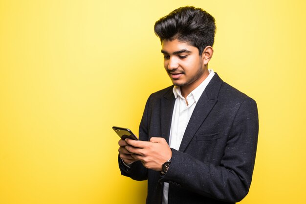 Asianindian business man handsome man using smart phone on yellow wall