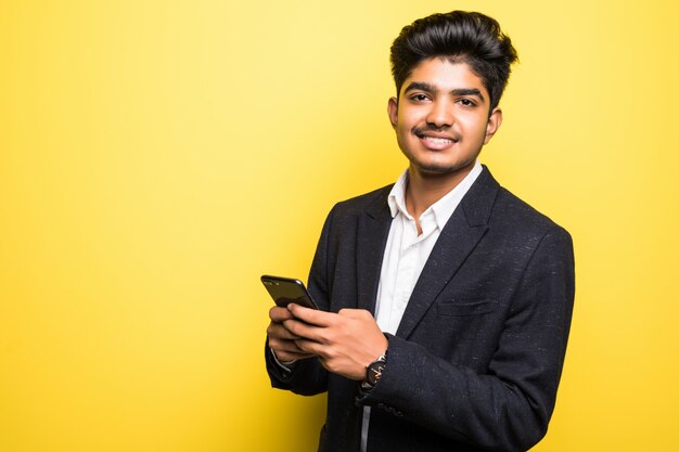 Asianindian деловой человек красивый человек, используя смартфон на желтой стене