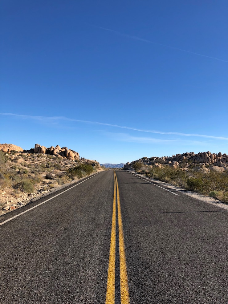 Free Photo asphalt road with yellow lines under a clear blue sky
