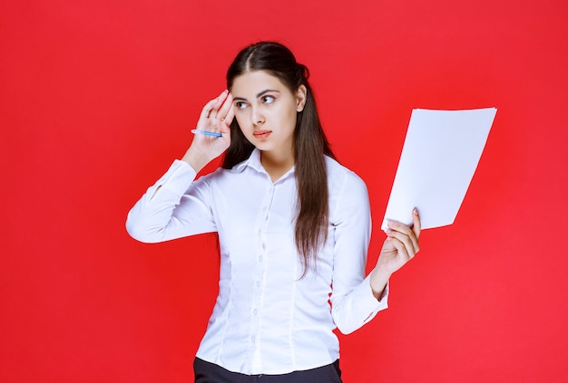 Assistant holding reporting lists and thinking.