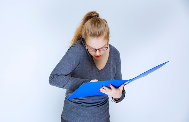 Assistant opening the blue report folder and checking it.