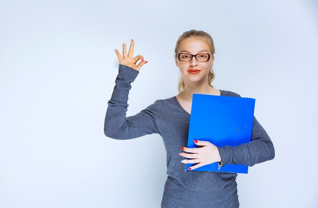 Assistant with a blue folder showing positive hand sign.