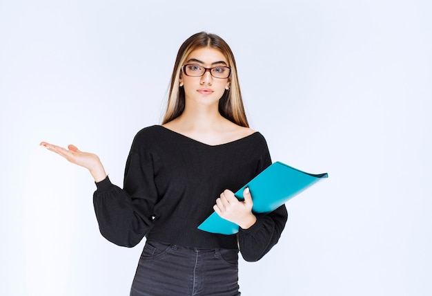 Assistant with eyeglasses holding a blue folder and showing the guests the direction. High quality photo