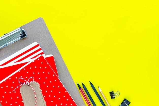 Assorted colorful stationery for school and office on yellow background with copyspace.