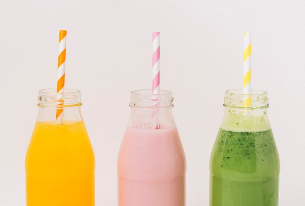 Assorted delicious fruit smoothies in bottles with straws