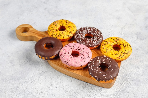 Assorted desserts with chocolate frosted, pink glazed and sprinkles.