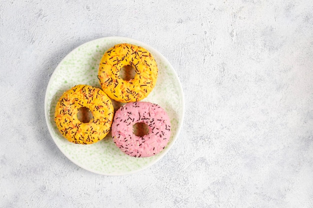 Assorted donuts with chocolate frosted, pink glazed and sprinkles.