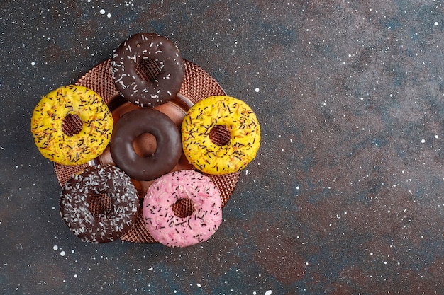 Free photo assorted donuts with chocolate frosted, pink glazed and sprinkles.