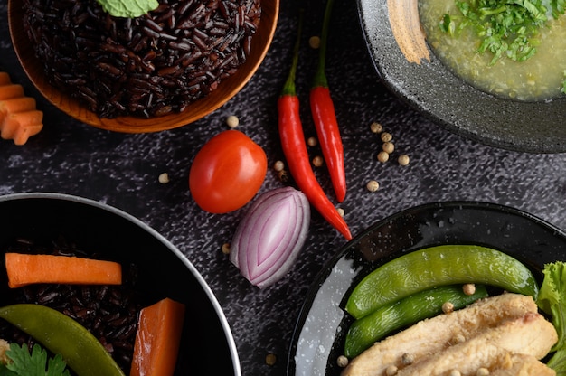 Assorted food and dishes of vegetables, meat and fish on a black stone table. top view.