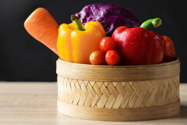 木製のテーブルの上のバスケットに新鮮な野菜の盛り合わせ