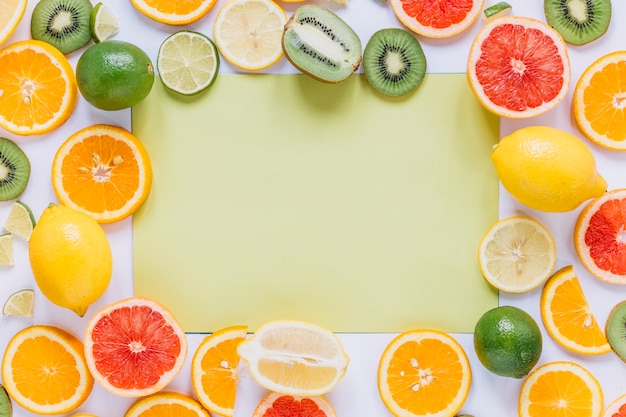 Assorted fruits around green paper sheet