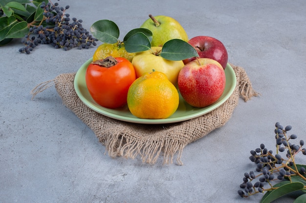 Piatto di frutta assortita su un pezzo di stoffa su sfondo di marmo.