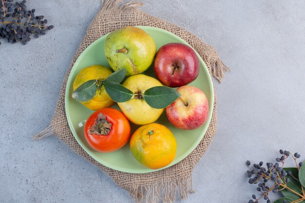 Assorted fruits platter on a piece of cloth on marble background. 