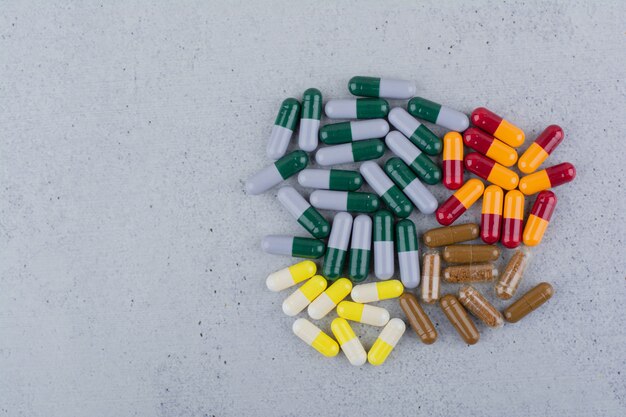 Assorted medical capsules on marble surface. 