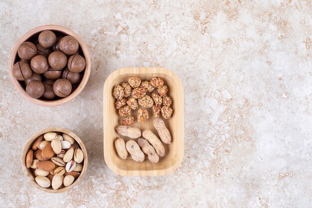 Assorted nuts in bowls next to a bowl of chocolate balls 