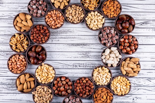 Assorted nuts and dried fruits in a cycle shaped mini different bowls with pecan, pistachios, almond, peanut, top view