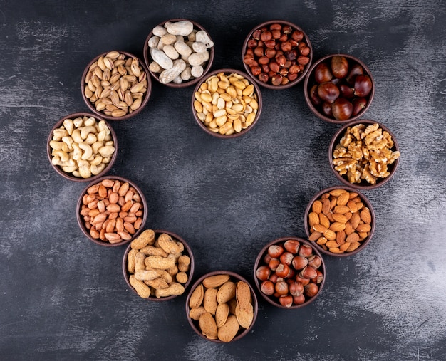 Assorted nuts and dried fruits in a heart shaped mini different bowls with pecan, pistachios, almond, peanut, top view