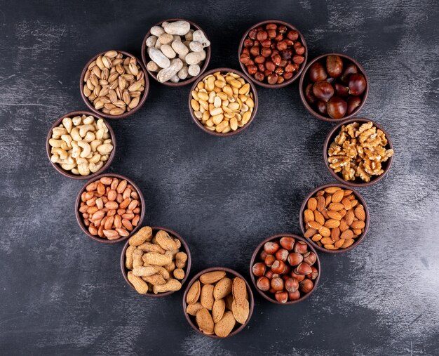 Assorted nuts and dried fruits in a heart shaped mini different bowls with pecan, pistachios, almond, peanut, top view