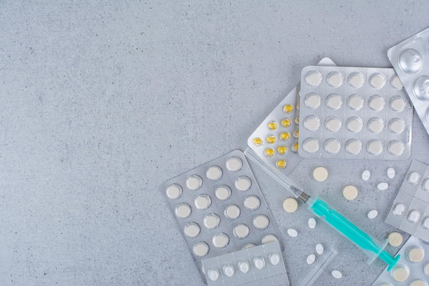 Assorted packs of drugs and empty syringe on marble surface