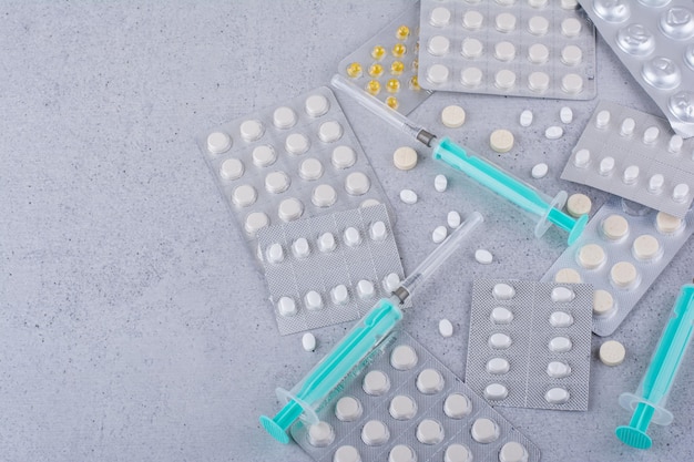 Assorted packs of drugs and empty syringes on marble surface. High quality photo