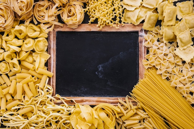 Assorted pasta around blackboard