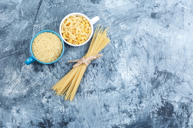 Foto gratuita pasta assortita in ciotole su uno sfondo di gesso grigio. vista dall'alto.