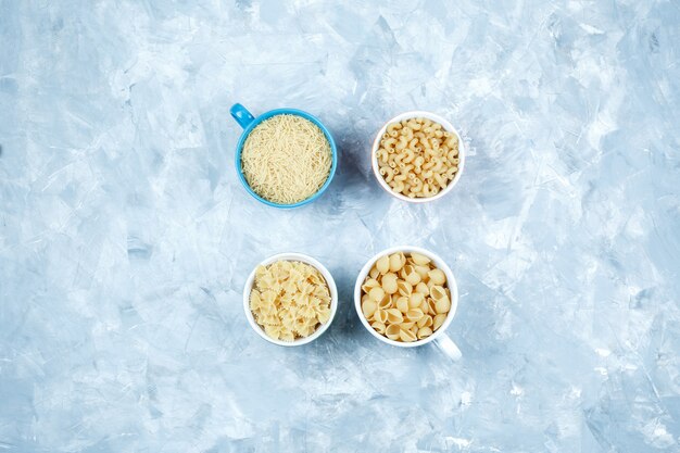 Free photo assorted pasta in bowls on a grungy grey background. top view.