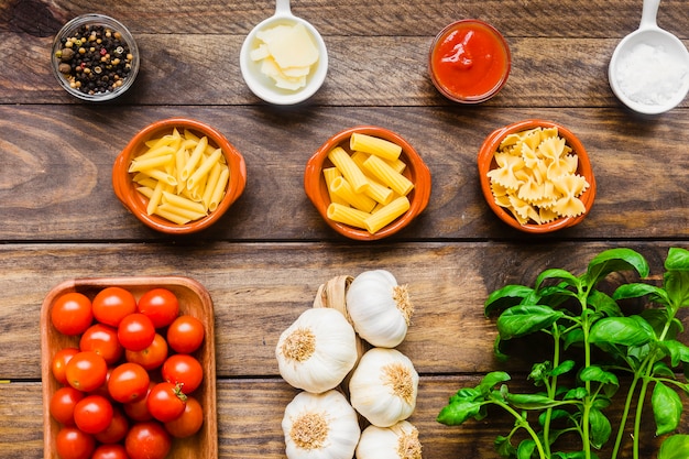 Assorted pasta and condiments near vegetables