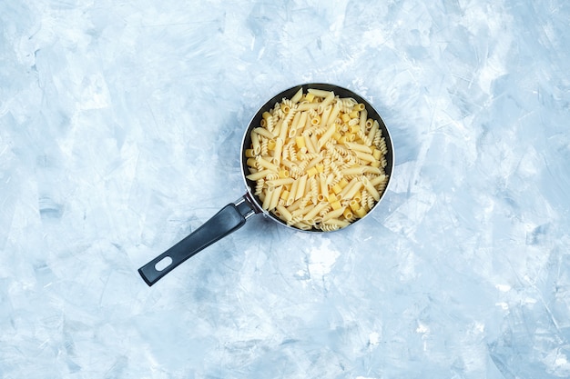 Foto gratuita pasta assortita in una vista dall'alto di padella su uno sfondo grigio sgangherata