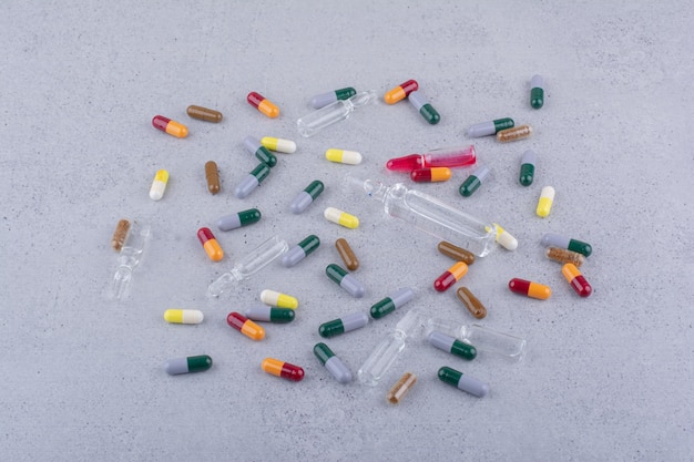 Capsule e fiale farmaceutiche assortite sulla superficie di marmo. foto di alta qualità