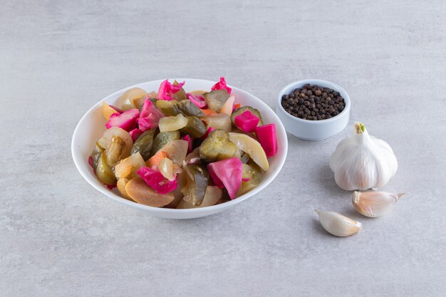 Assorted pickles vegetables placed on a stone surface. 