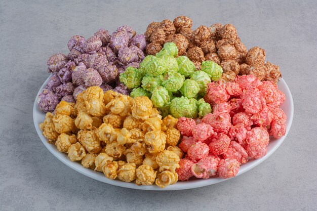 Assorted popcorn candy served in small glass bowls on marble.