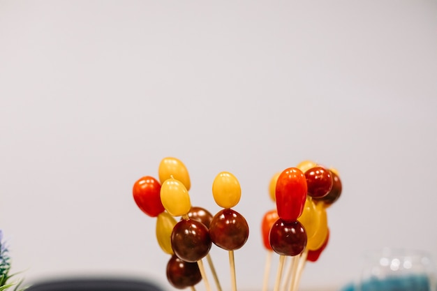 Free photo assorted red and yellow cherry tomatoes on wooden sticks on white background. copy space. snack and food concept.