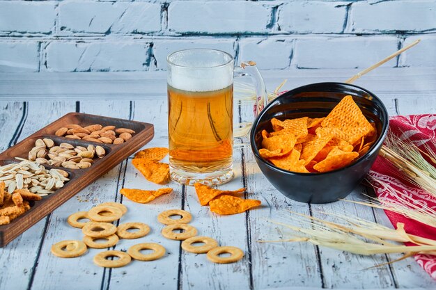 Assorted snacks, chips, and a glass of beer on blue table.