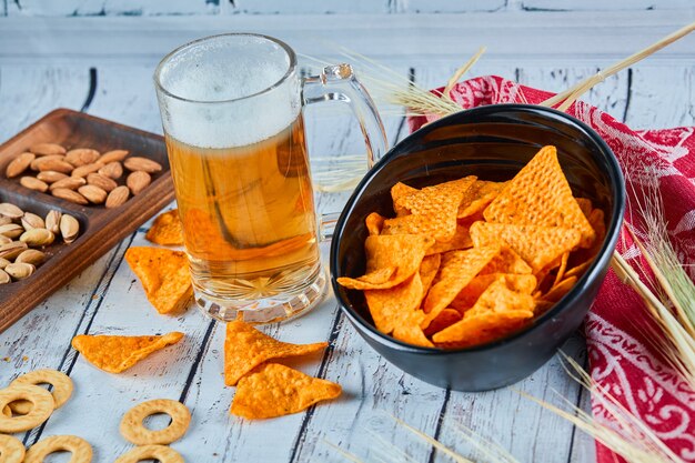 Assorted snacks, chips, and a glass of beer on blue table.