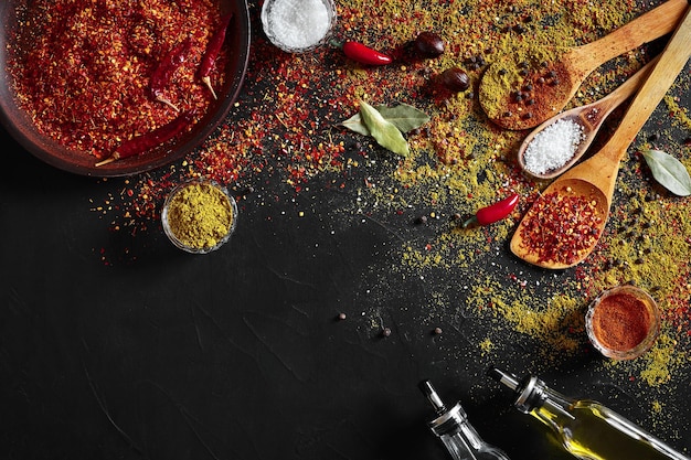 Assorted spices on dark black background. Seasonings for food. Curry, paprika, pepper, cardamom, turmeric. Top view. Close-up. Spices concept. Spices ingredients for cooking