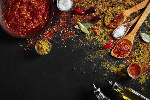 Assorted spices on dark black background. Seasonings for food. Curry, paprika, pepper, cardamom, turmeric. Top view. Close-up. Spices concept. Spices ingredients for cooking