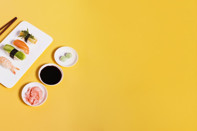 Assorted sushi and condiments on yellow