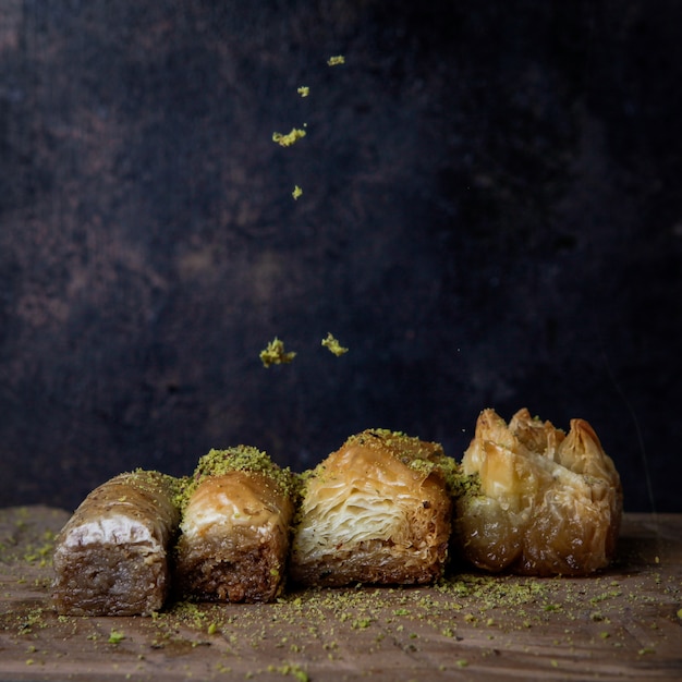 Foto gratuita baklava turca assortita con pistacchi macinati in zolla di legno