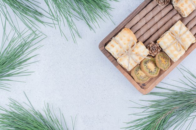 Assortment of biscuits and dried kiwi on wooden board. 