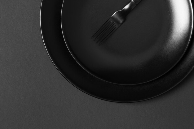 Ассортимент черных тарелок на черном фоне